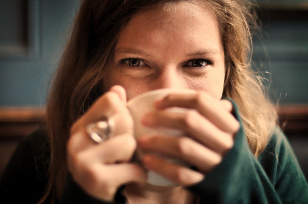 A girl smiling while holding a cup of coffee, ready to start her day.