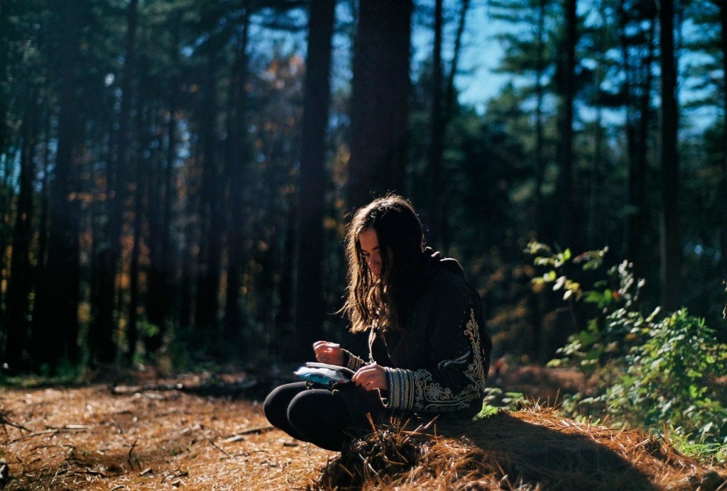 A girl sitting in the forest, reflecting while examining a map.