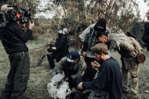 Actors in costume checking footage on the set of 'Dark Arrows' feature film, symbolizing character development and storytelling in writing.